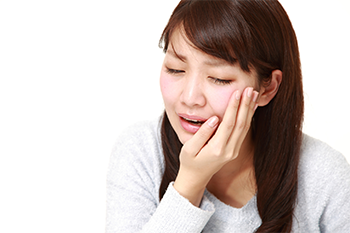 頬に手を当て痛がっている女性