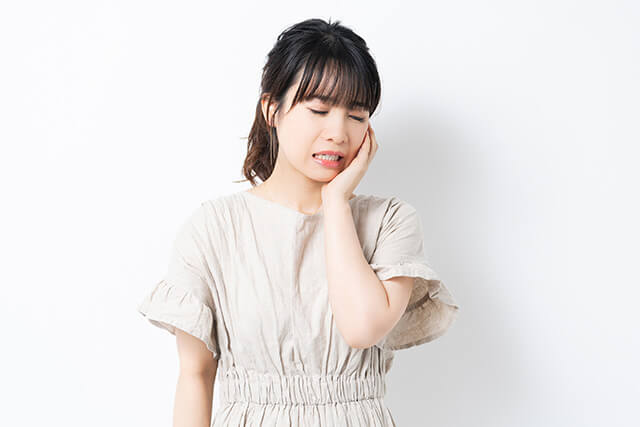 頬に手を当て痛がっている女性